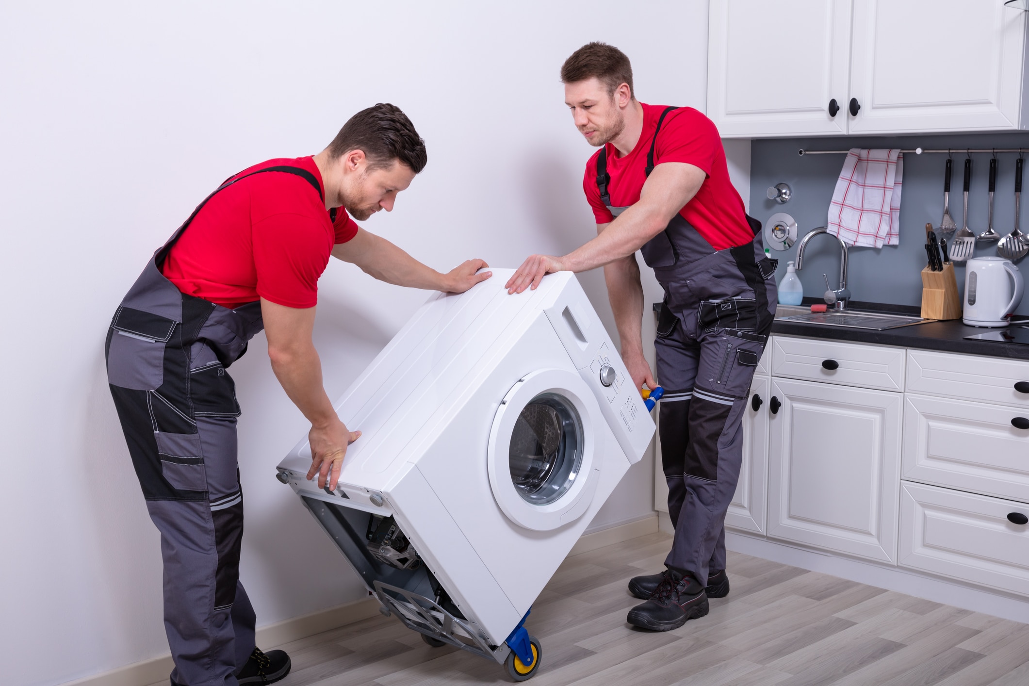 Young Male Mover Carrying Home Appliances In Kitchen
